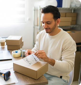 Person placing a shipping label on a shipping box.